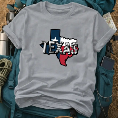 Gray t-shirt with Texas state outline design on a backpack and camping gear background