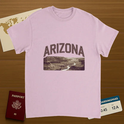 light pink Arizona USA Unisex Travel T-Shirt on wooden background with world map, passport, and boarding pass