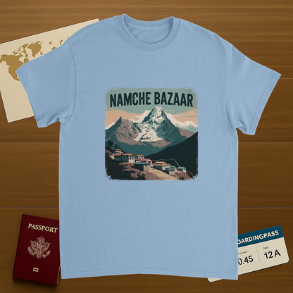light blue Namche Bazaar Nepal Unisex Travel T-Shirt on wooden background with world map, passport, and boarding pass